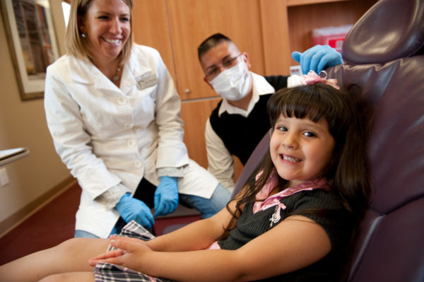 Child patient sitting with healthcare providers, possibly for a doctor's visit or checkup.